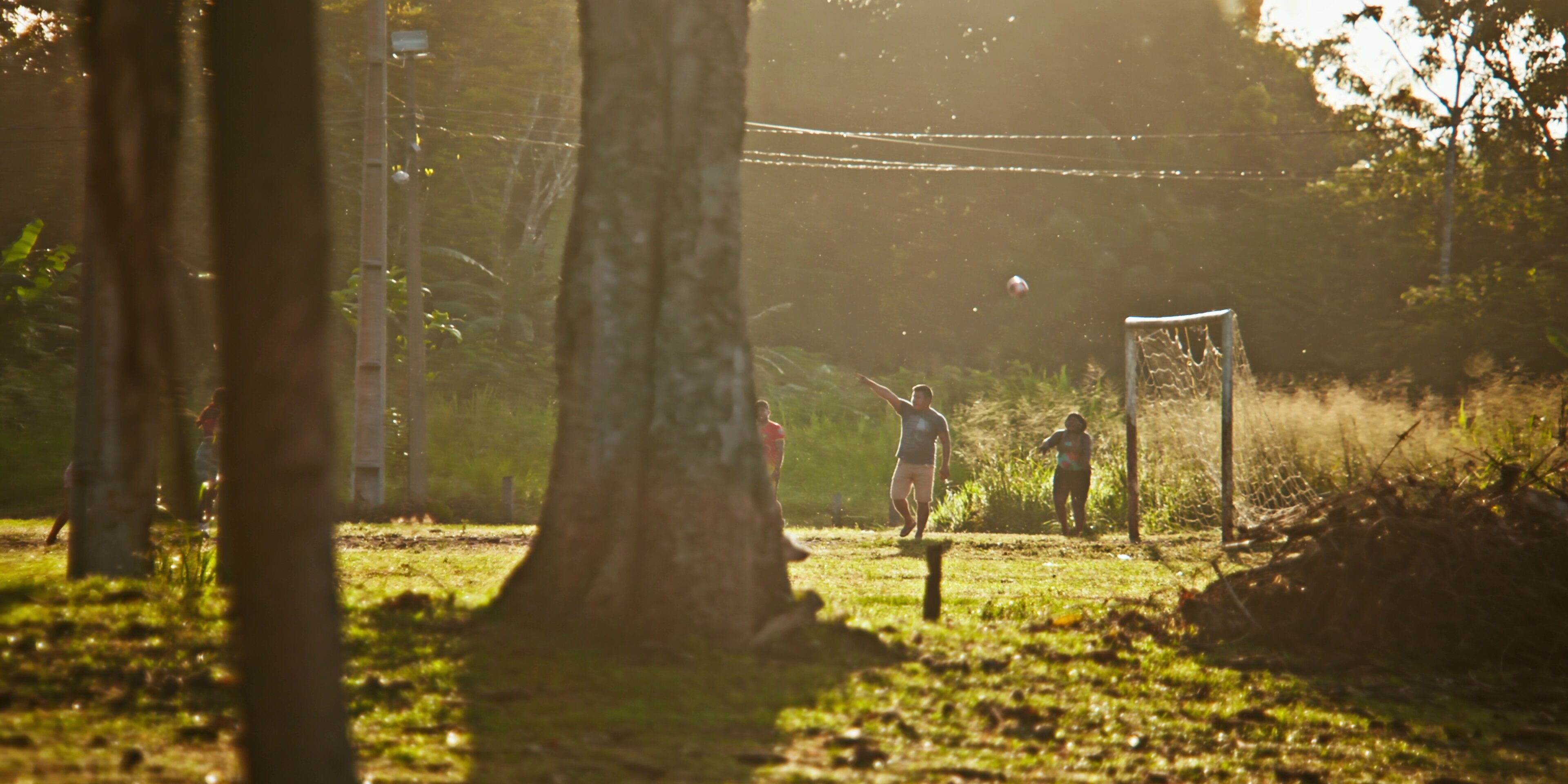 Crianças jogando futebol ao pôr do sol